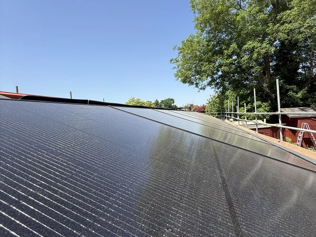 Row of black in-roof solar panels under a blue sky