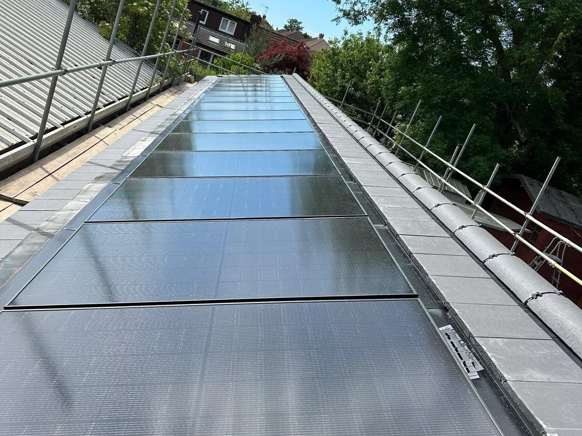Long run of in-roof solar panels between slate-effect tiles