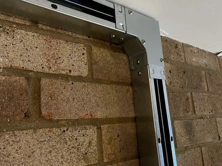 Galvanised trunking turning a corner on a brick wall