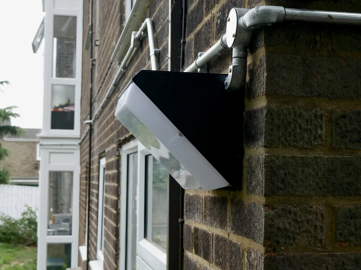 External LED bulkhead on a block of flats, fed by steel conduit