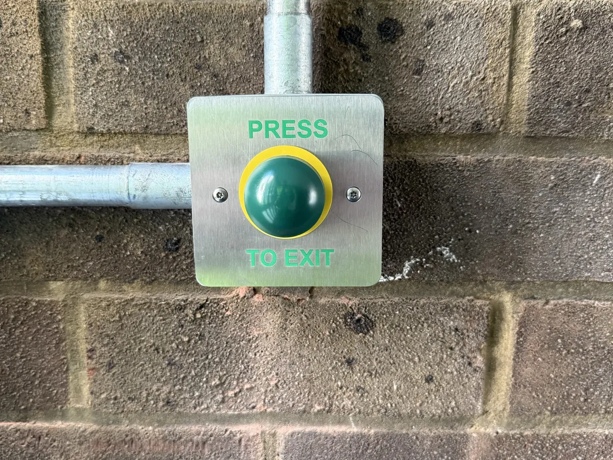 Press-to-exit button on a brick wall