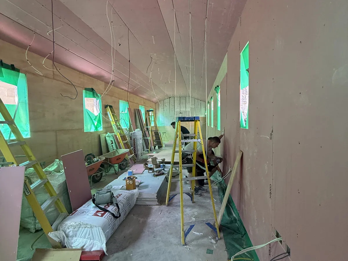 First-fix cables hanging in a boarded building with ladders