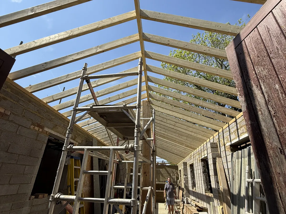 New building under construction with roof rafters and a scaffold tower