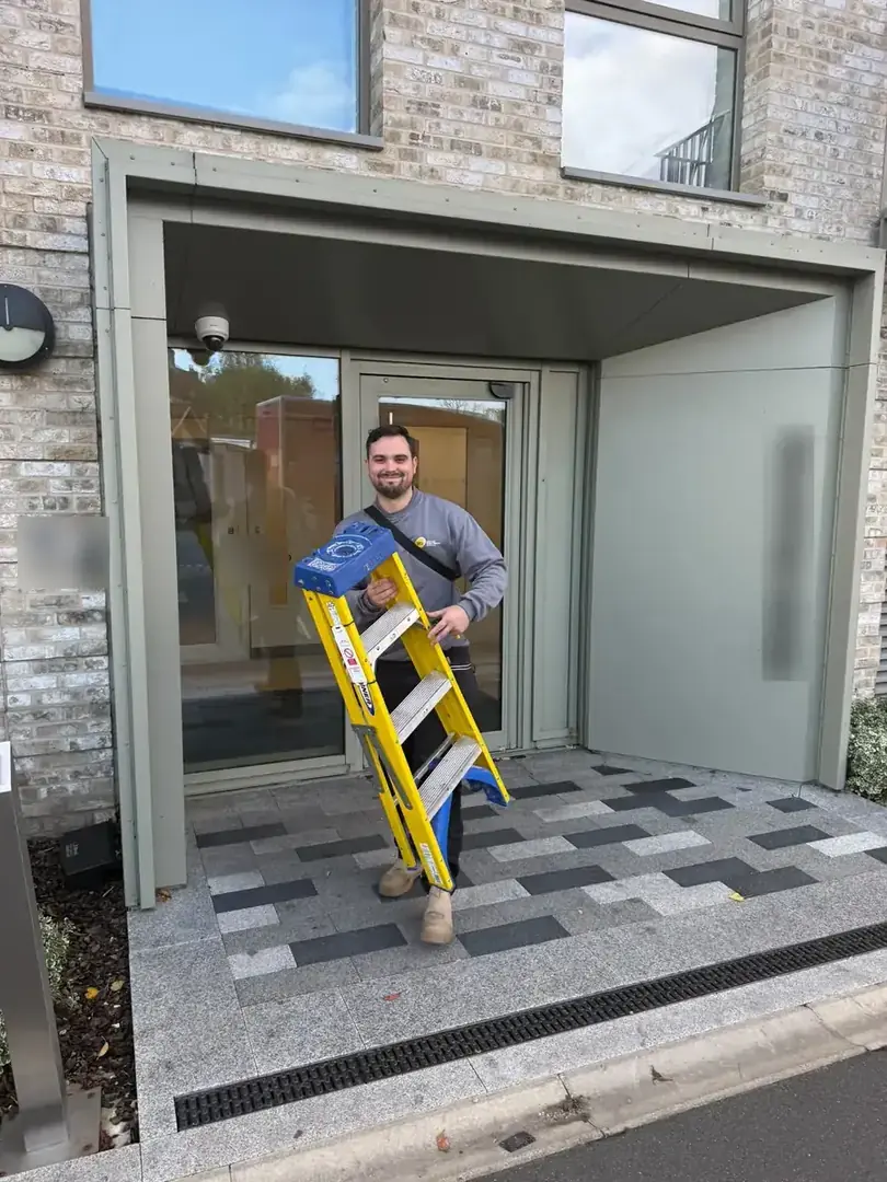 SEG engineer carrying steps out of a block of flats in Wembley after testing