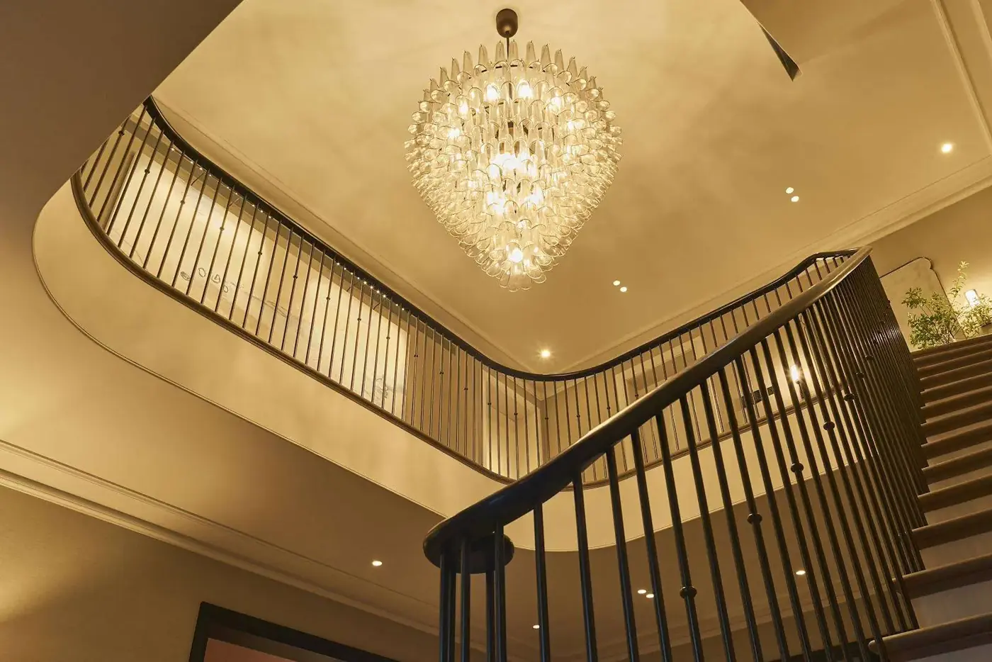 Stairwell with crystal chandelier and lit balustrade