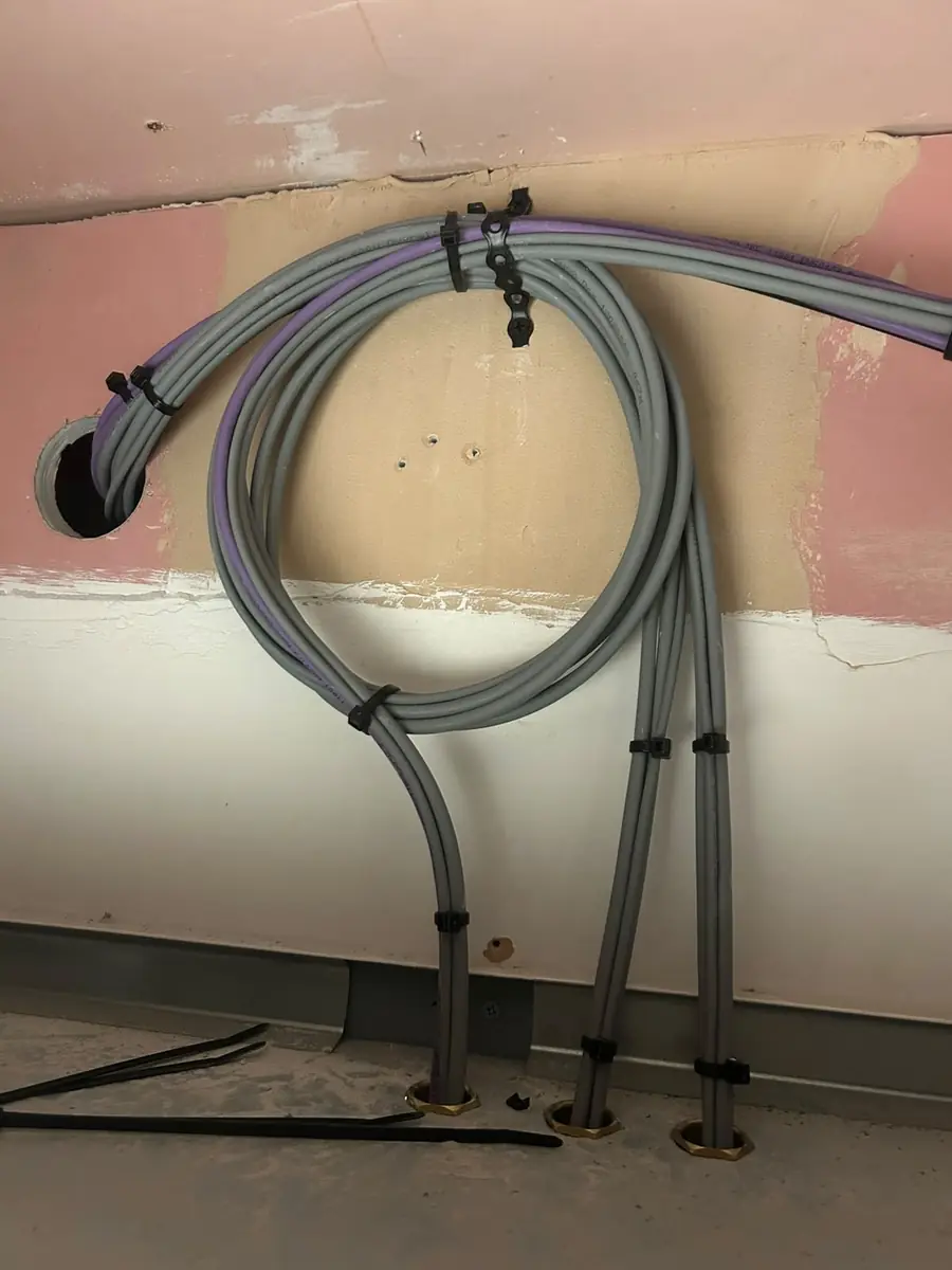 Door cables brought down through the wall void, dressed with a tidy service loop and fixed with saddles before they enter the enclosure