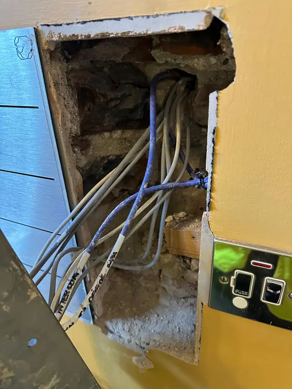 Behind the old entry panel: the cables come through solid masonry