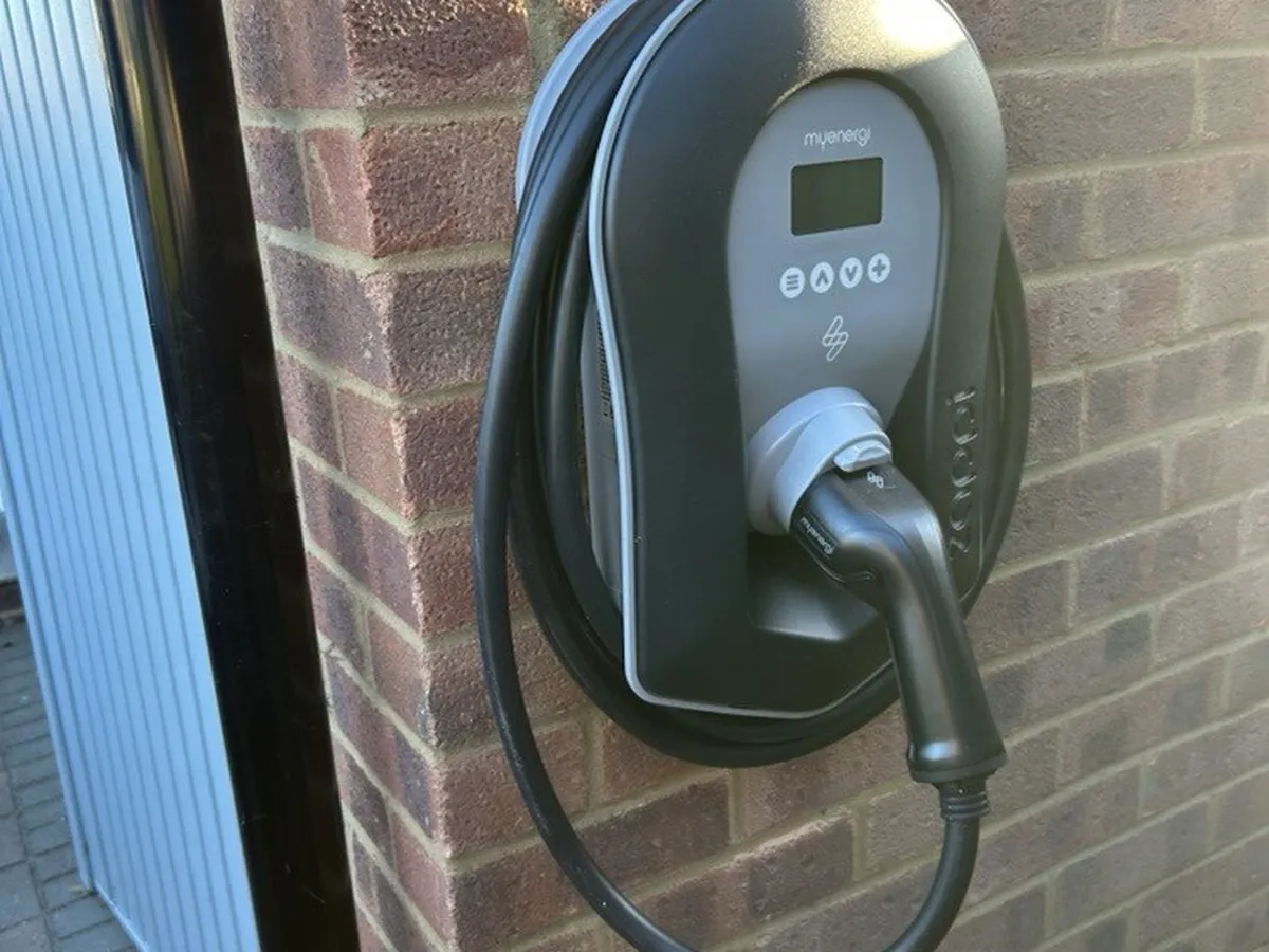 Black tethered myenergi Zappi charger on the side of the garage