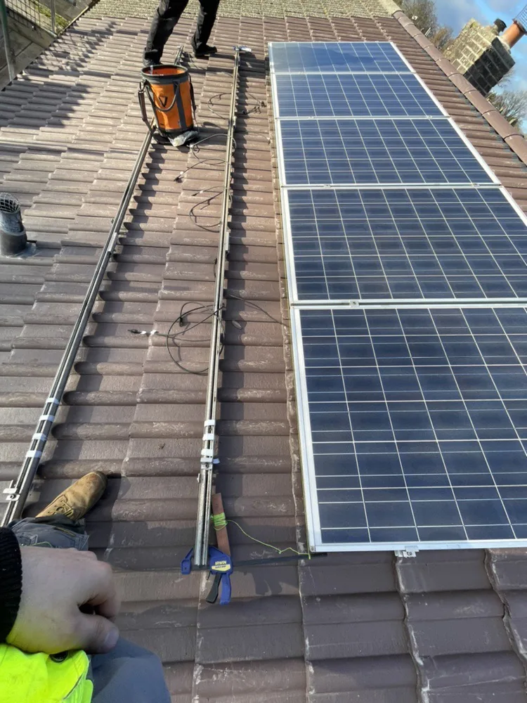 Solar panels being refitted on a new tiled roof with a string line along the rails