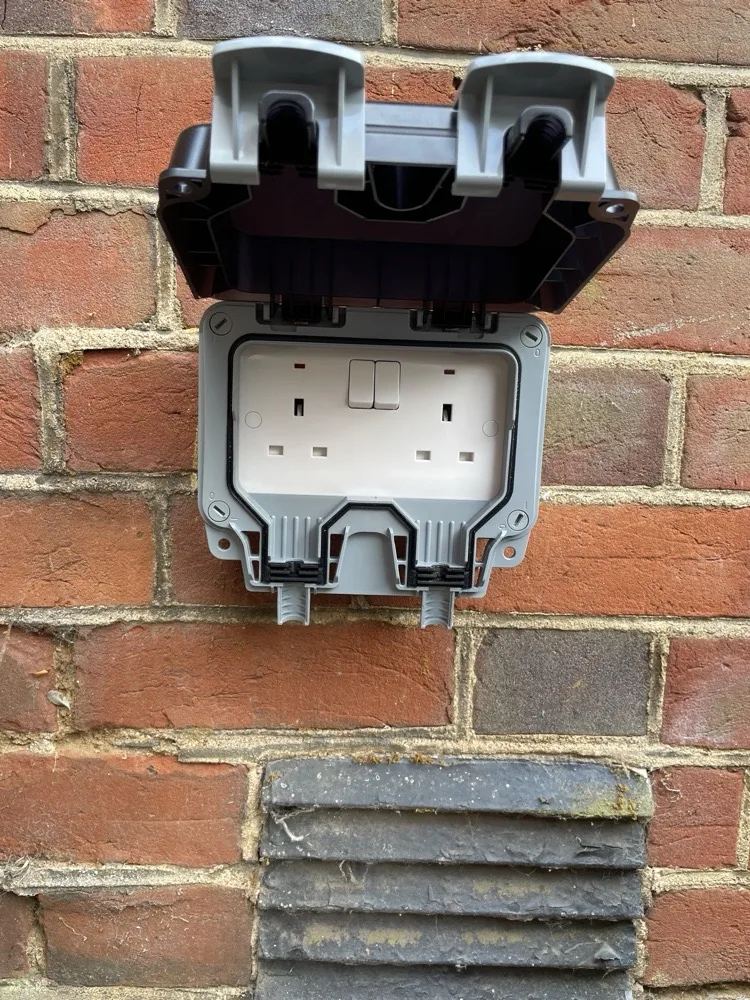New weatherproof outdoor double socket fitted on a brick wall