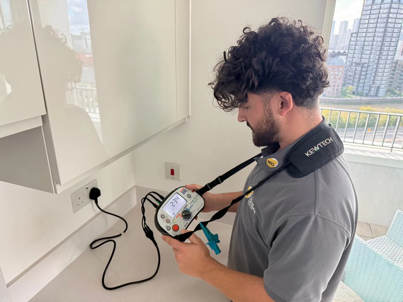 SEG engineer testing a kitchen socket circuit with a Kewtech multifunction tester in one of the flats