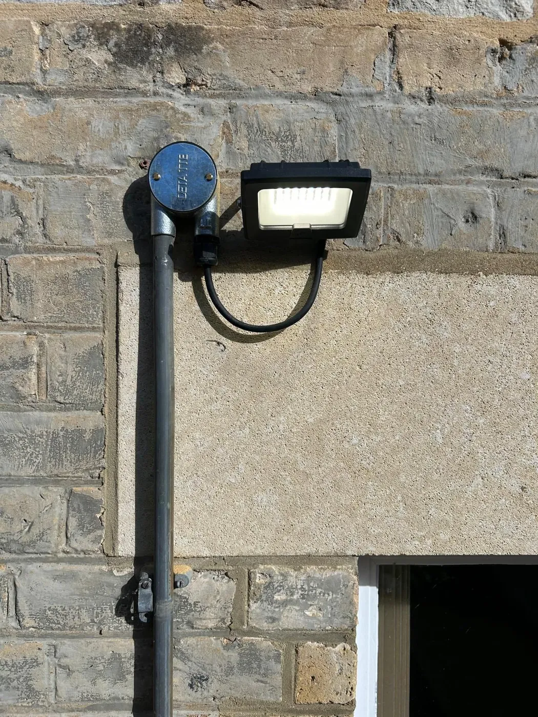 LED floodlight on a lighting column above an entrance