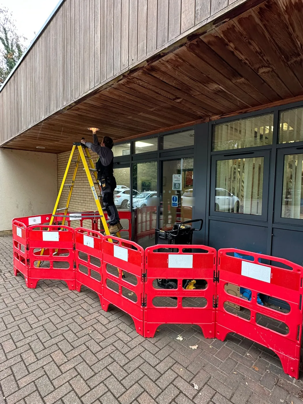 SEG electrician fitting a new soffit light at a school entrance in Ware