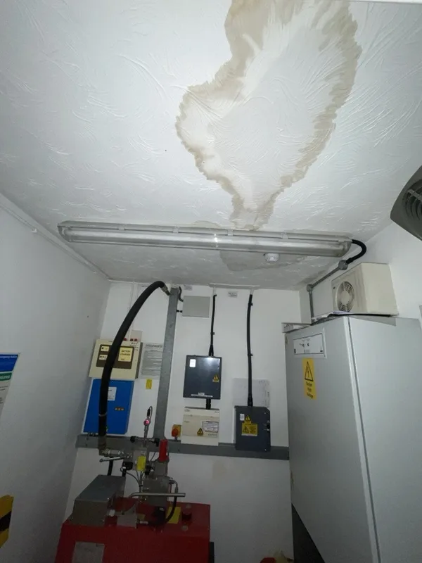 Water stain on the ceiling above a light in a lift motor room