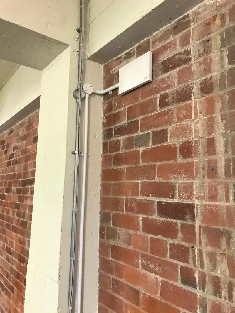 Wall-mounted Wi-Fi access point on brickwork with conduit
